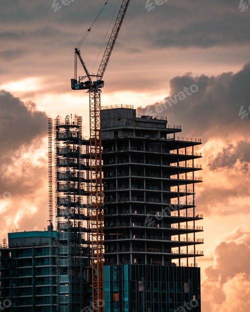 Preview: Vertical shot of a crane building a skyscraper during a sunset