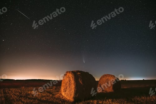 Preview: Meteor And Comet Neowise C2020 F3 In Night Starry Sky Above Haystacks In Summer Agricultural Field