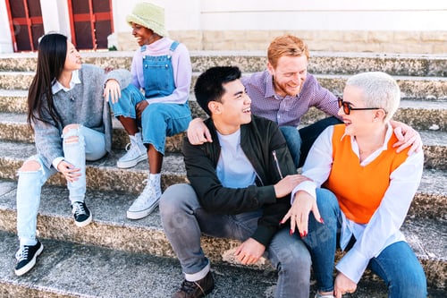 Preview: Group of friends enjoying the weekend sitting outdoors. Multiethnic people talking in stairs.
