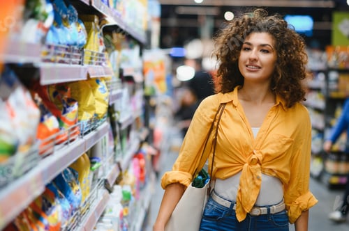 Preview: Woman shopping for groceries in supermarket aisle