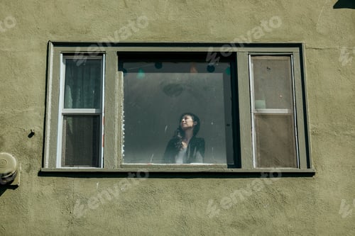 Preview: Woman looking out the window of her downtown LA apartment during the covid-19 pandemic