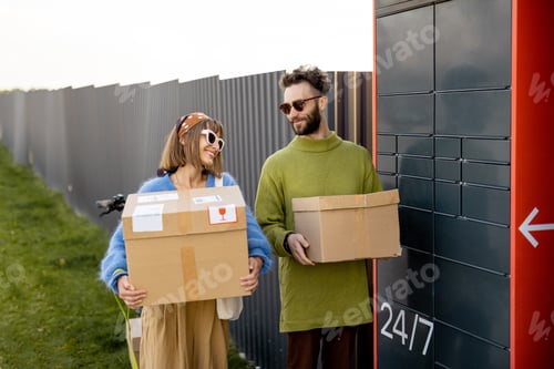 Preview: Man and woman carry parcels received in automatic post machine outdoors