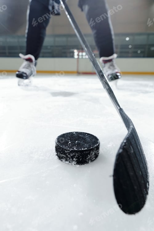 Preview: Legs of male hockey player in sports uniform and skates going to shoot puck