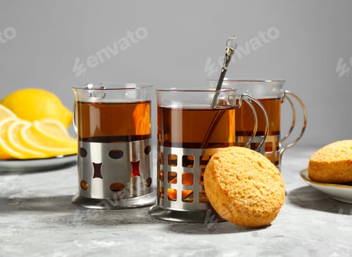 Preview: Glasses of tea in metal holders served on grey textured table, closeup