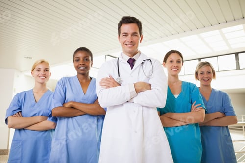 Preview: Smiling Doctor And Nurses With Arms Crossed In Hospital Corridor
