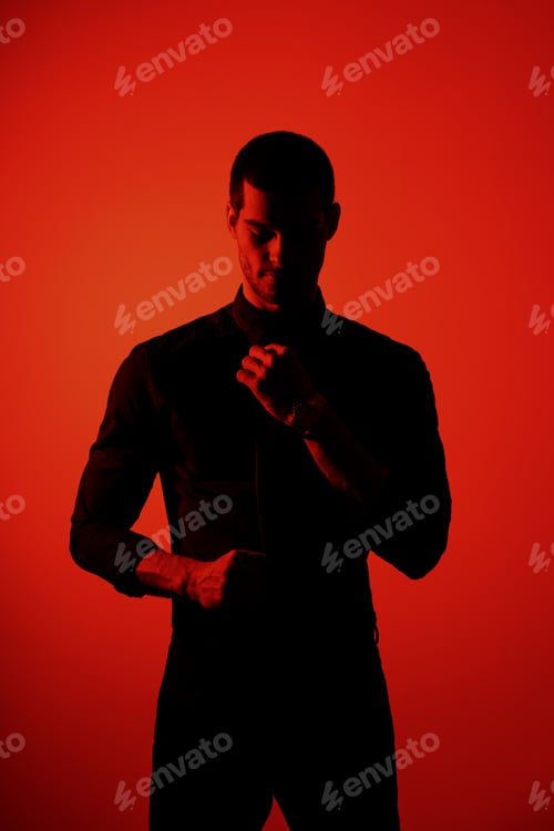 Preview: Silhouette of a young confident handsome businessman wearing black shirt in red light