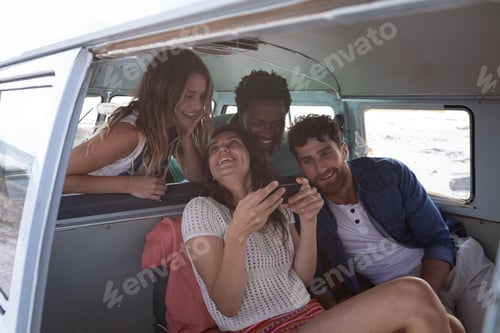 Preview: Group of friends interacting with each others in a camper van at beach