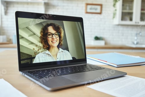 Preview: Close up of laptop screen with attractive female teacher smiling during video call, having online