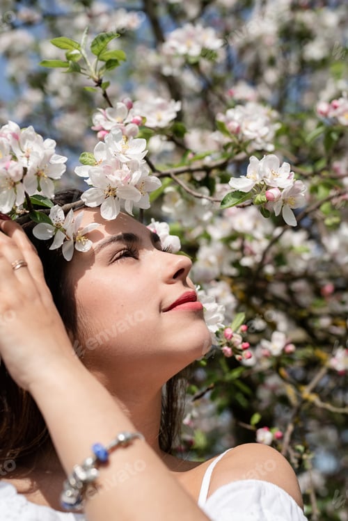 Preview: Young caucasian woman enjoying the flowering of an apple trees