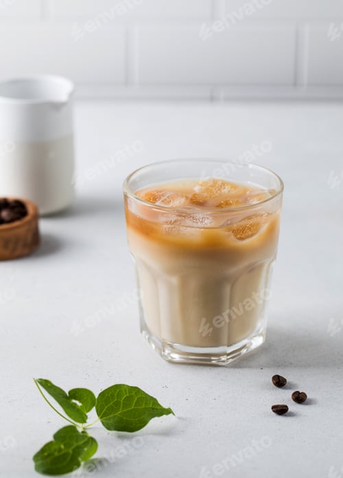 Preview: Cold coffee with ice and cream on a white tile background. Homemade cold latte.