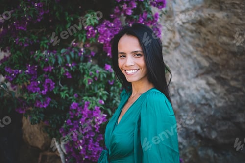 Preview: Smiling ethnic woman standing in blooming flowers garden
