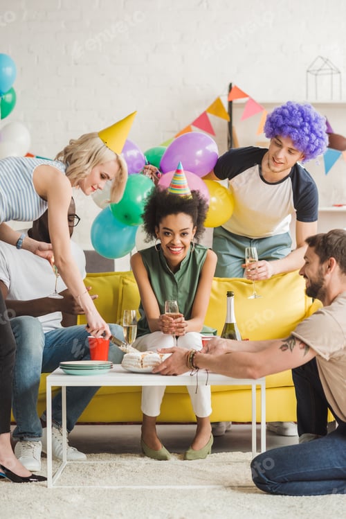 Preview: Young friends greeting african american woman with birthday cake