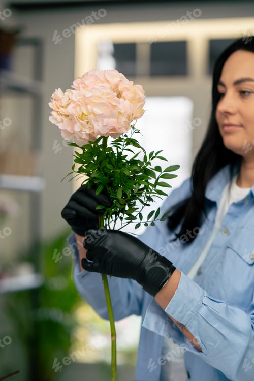 Preview: close up flower shop girl near a white table collects a flower arrangement of a beautiful bouquet of