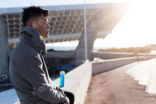 Preview: Fit and sporty young man relaxing after work out in the city.