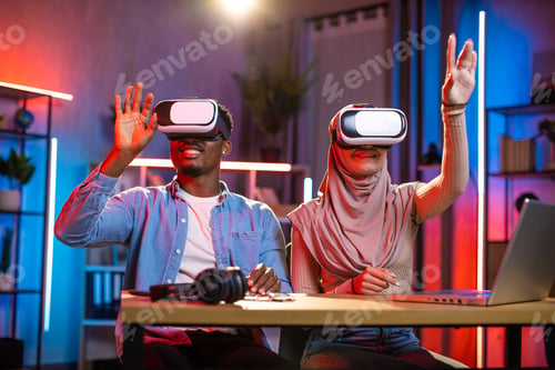 Preview: Young multicultural couple playing games in VR goggles