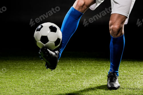 Preview: cropped view of sportsman playing with ball on grass isolated on black