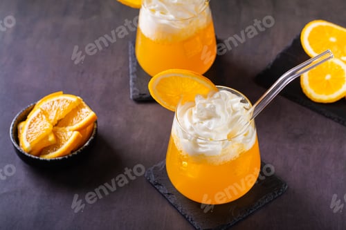 Preview: Dirty orange soda with whipped cream in glasses and orange slices on the table