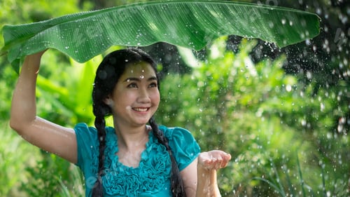 Preview: Asia woman with black hair holding a banana leaf in the raining