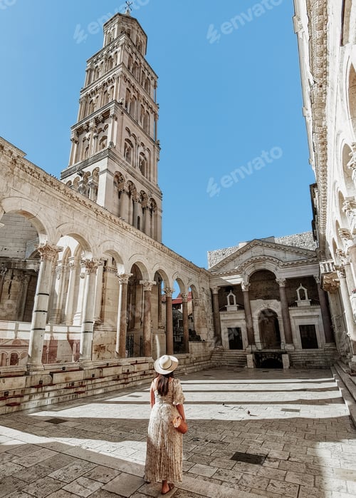 Preview: Woman in stylish summer dress standing in Peristyle of Diocletian's palace in Split, Croatia.