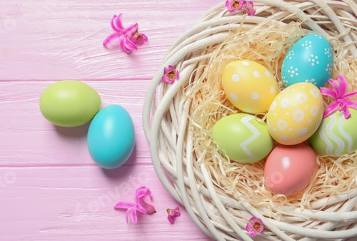 Preview: Flat lay composition of wicker nest with painted Easter eggs on wooden table