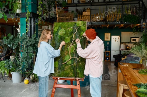 Preview: Two young hipster designers working on floral collage at florist shop