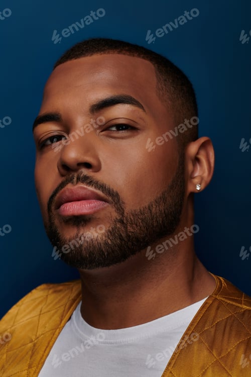 Preview: trendy african american male model with beard and diamond earring looking at camera, fashion concept