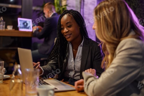 Preview: Two businesswoman having a meeting in a cafe while using a laptop