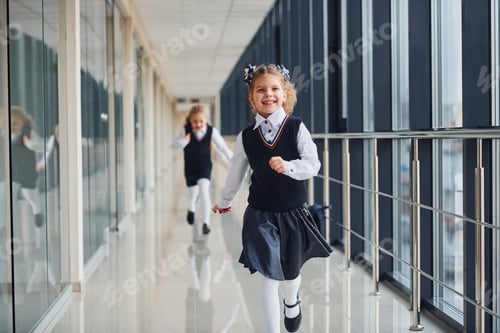 Preview: School girls in uniform running together in corridor. Conception of education