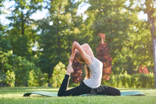Preview: Young woman practicing yoga outdoors at the park