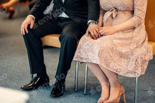 Preview: Closeup view of a loving couple sitting and waiting holding hands