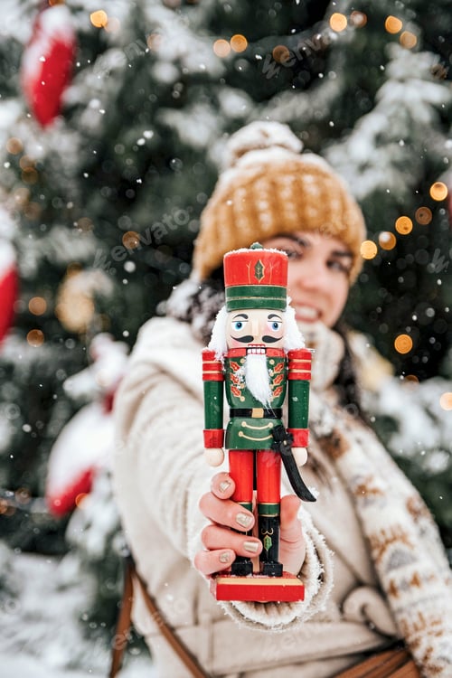 Preview: Selective focus image of woman holding nutcracker soldier toward camera.
