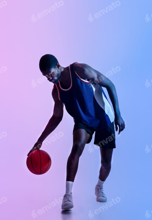 Preview: Full length portrait of determined black basketballer playing ball in neon lighting