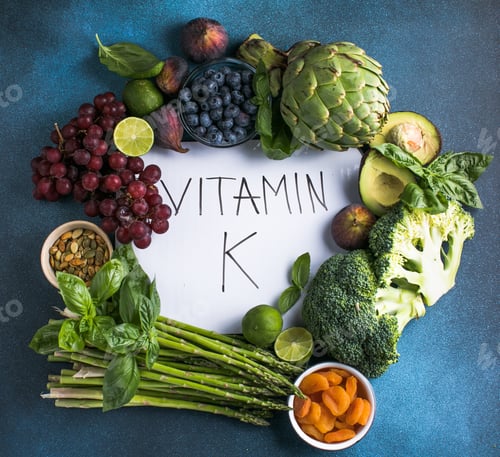 Preview: Vegetables, fruits and text Vitamin K on blue background. Top down view