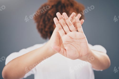 Preview: Closeup, hands and woman in studio for stop, warning or domestic violence symbol on grey background