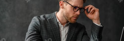 Preview: A peering man looking into the laptop screen while sitting at a table in the studio