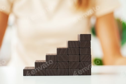 Preview: Women's hand folds black wooden cubes forming up stairs