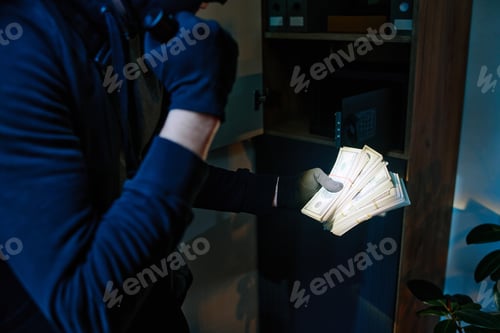 Preview: Young Adult Man Stealing Cash from Safe in Office during Nighttime Robbery