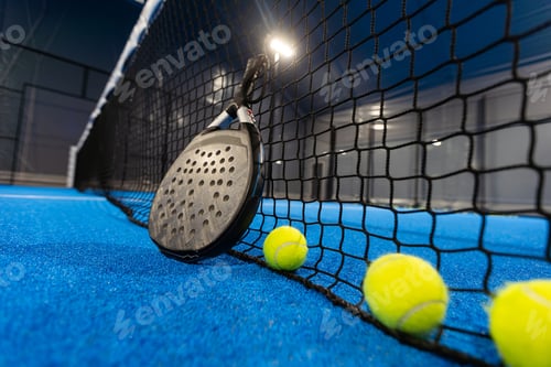 Preview: balls near the net of a blue padel tennis court