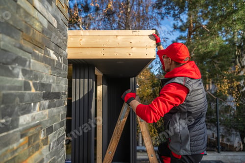 Preview: Worker Builds Wooden Structure Outside House