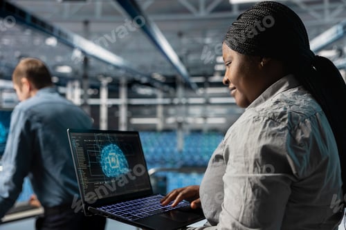 Preview: Smiling IT expert in server room using laptop to improve AI systems