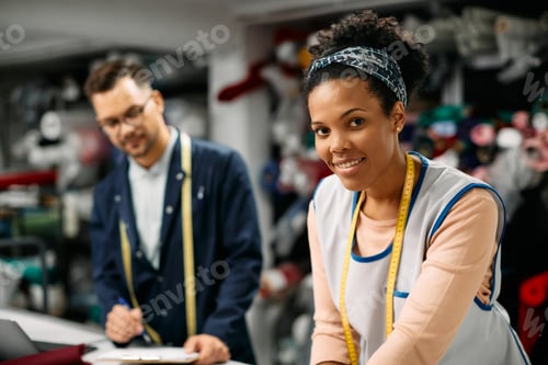 Preview: Smiling Fashion Designer with Man Taking Notes Nearby
