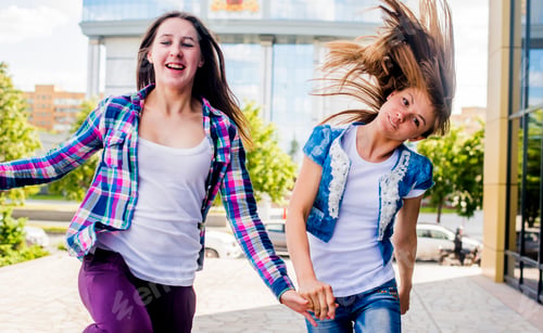 Preview: Two young women shaking their hair and running in city