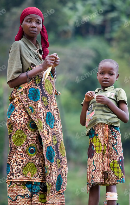 Preview: Mother and child standing in lush greenery wearing traditional African garments.