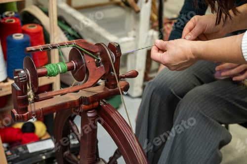 Preview: Distaff Day Close-up of adult spinning yarn on traditional spinning wheel