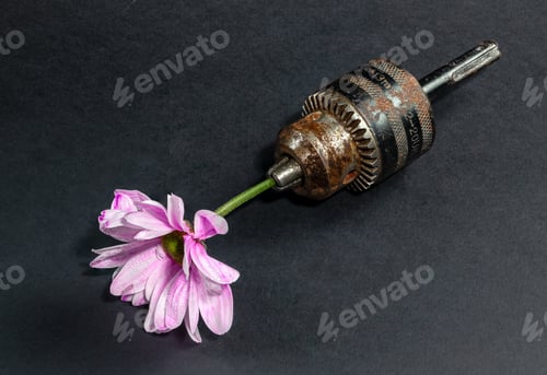 Preview: Old rusty drill head and chrysanthemum on a black background.