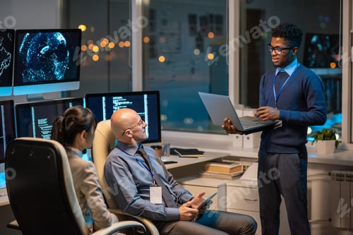 Preview: Young successful businessman with laptop making presentation for colleagues