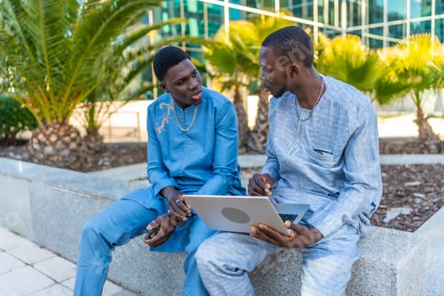 Preview: Senegalese businessmen wearing traditional dashiki using laptop outdoors
