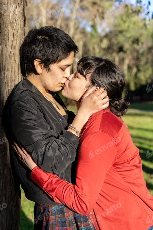 Preview: LGBT couple of women sharing a passionate kiss against a tree