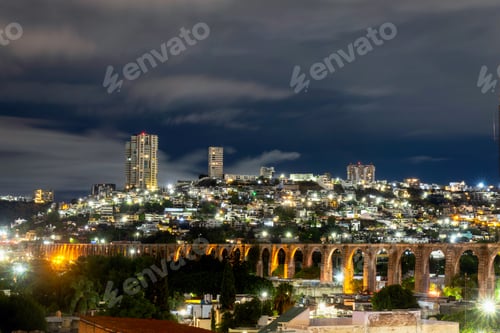 Preview: Night View of Illuminated Aqueduct of Queretaro Against a Modern Cityscape
