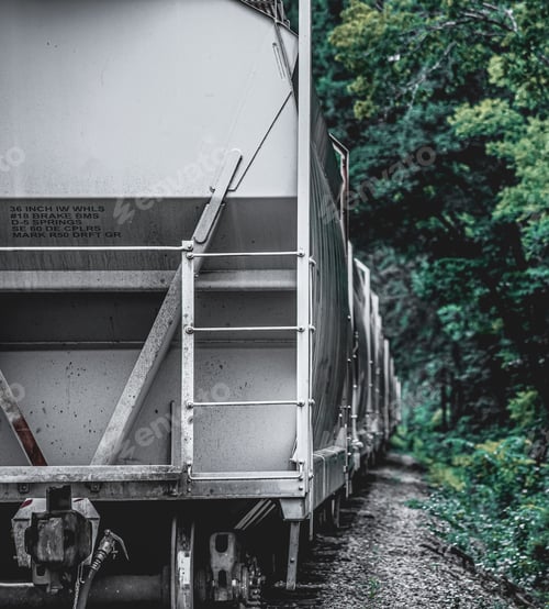 Preview: Closeup of train wagons lining rails in the distance trees around